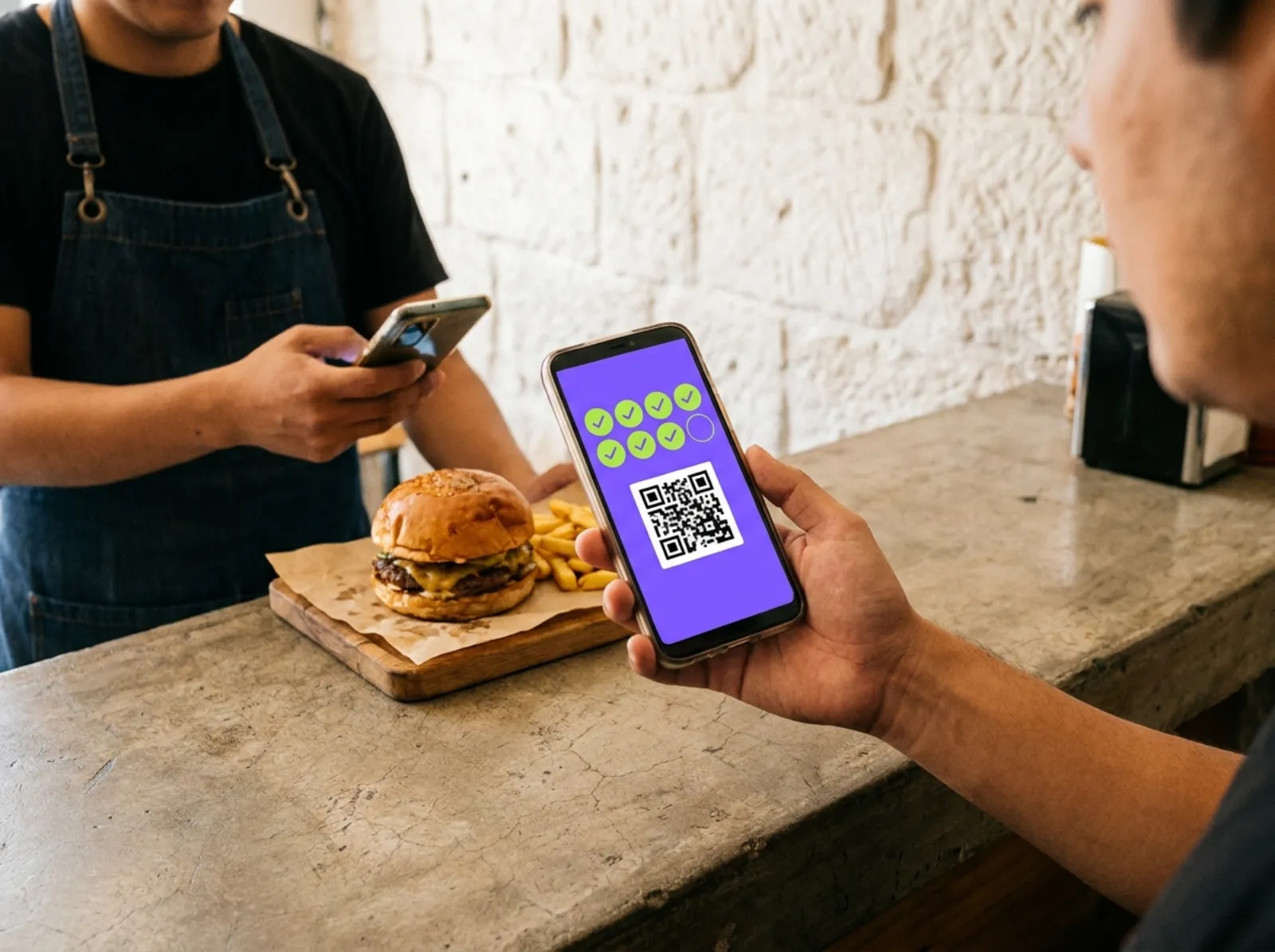Dans un restaurant de burgers, le personnel scanne la carte complète d'un client ; son burger offert l'attend sur le comptoir